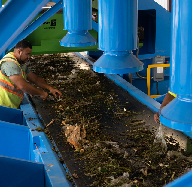 Green waste being processed through an organics recycling system