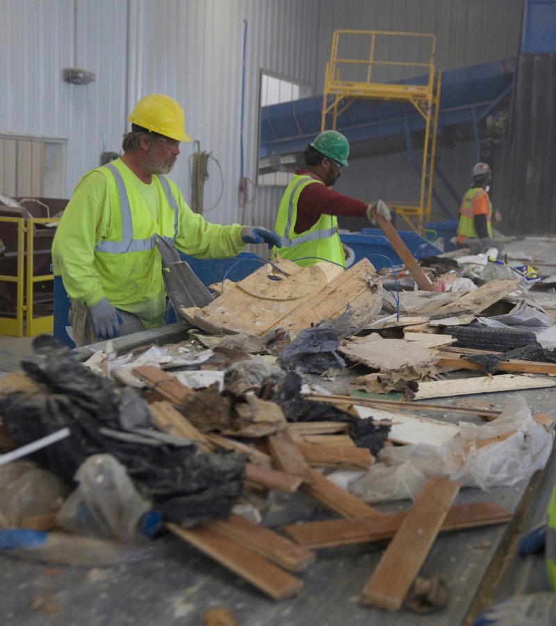 Workers sorting wood and other construction and demolition materials on a recycling line.